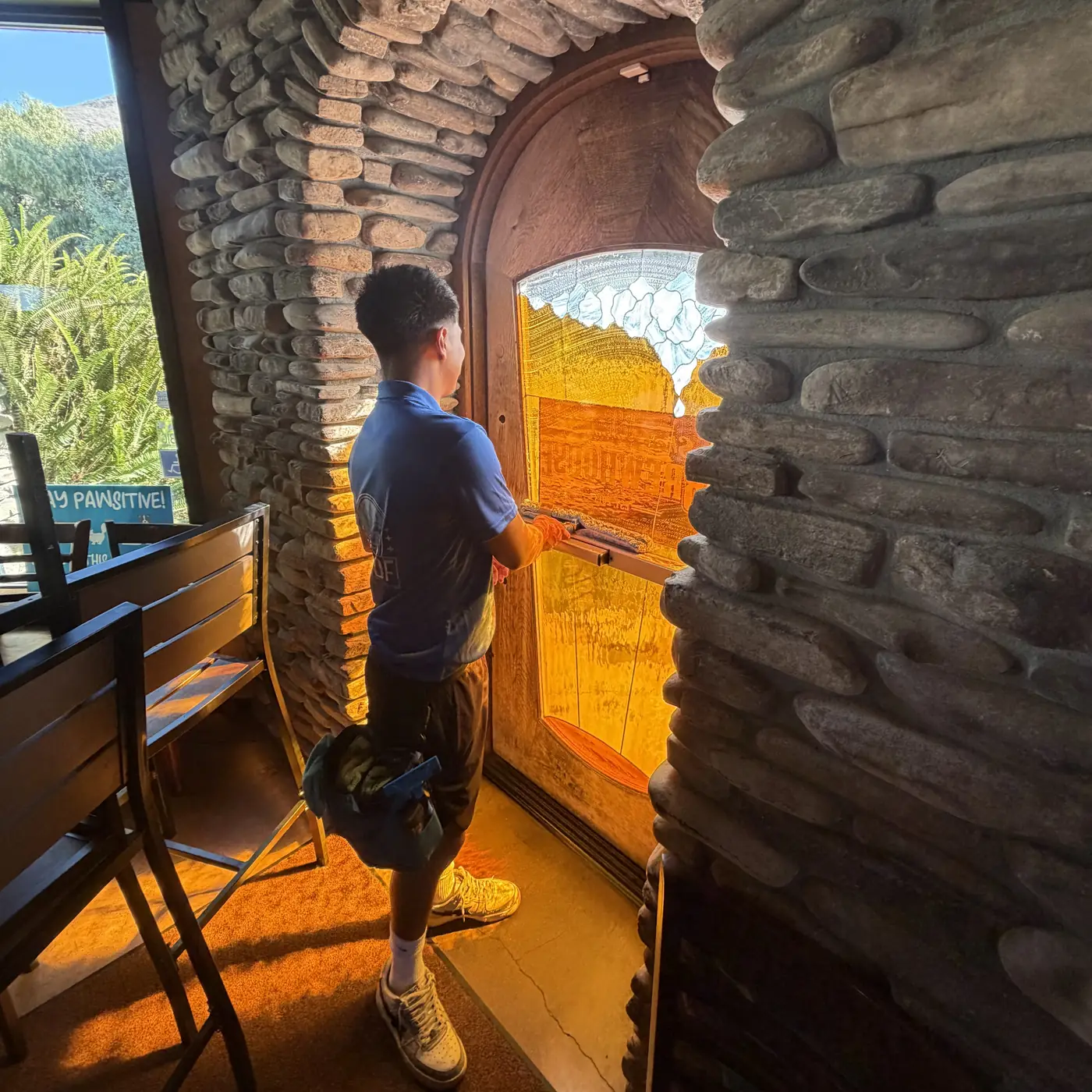 High Tide crew member cleaning the glass entry door of a business under a stone arch