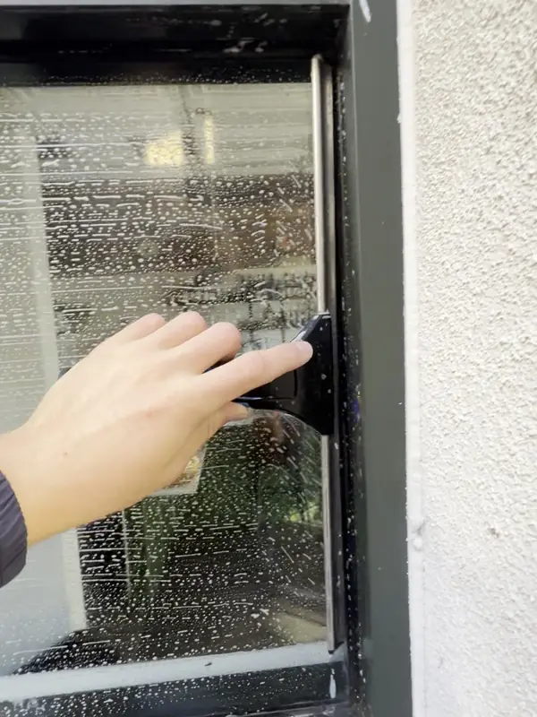 Before: Storefront window covered in cleaning foam as a High Tide crew member starts the squeegee pass, commercial window cleaning on the Central Coast