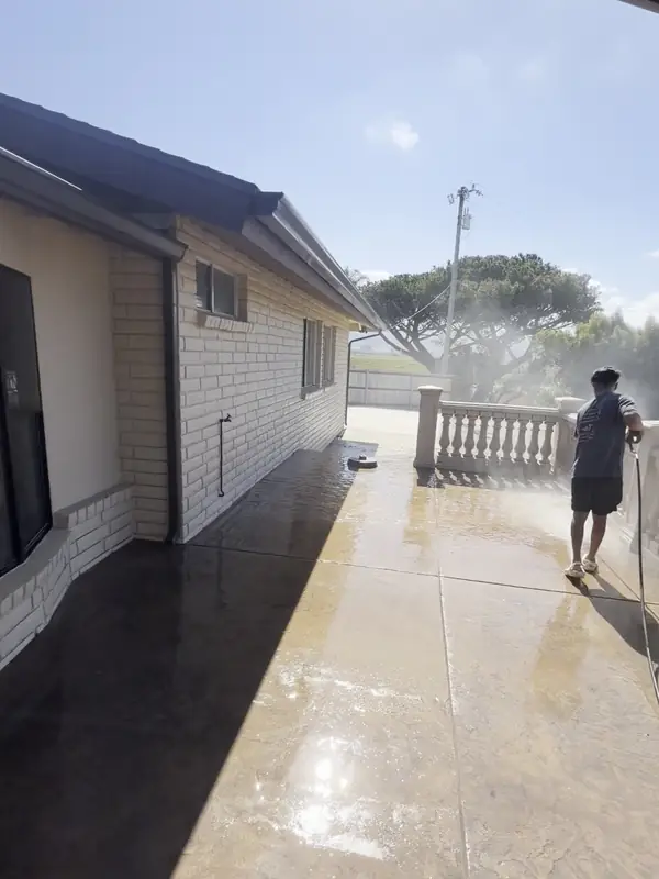 After: The same home's brick wall and patio after a High Tide cleaning, with the crew finishing the rinse