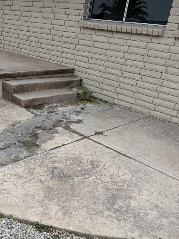 Before: Green mildew and dark stains where a home's painted brick wall meets the patio steps