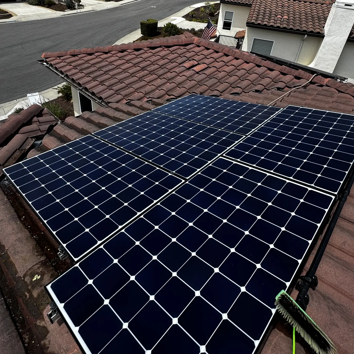 Rooftop solar panels on a tile roof after a High Tide cleaning, soft brush resting on the array