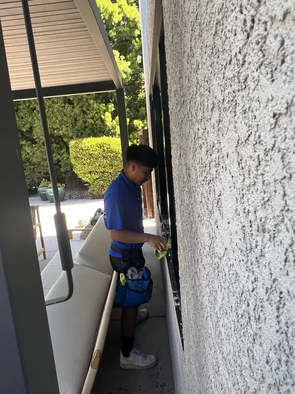 Before: High Tide crew member detailing a patio window frame by hand with a microfiber towel, window cleaning in Lompoc, CA